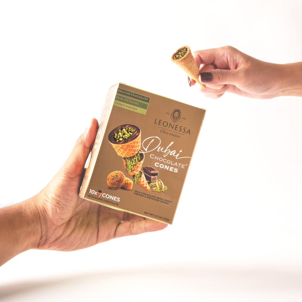 Hand holding Leonessa Dubai Chocolate Cones packaging with a cone held above it.