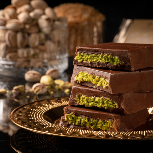 Cut open Dubai Chocolate Bars on a gold plate with pistachios in the background